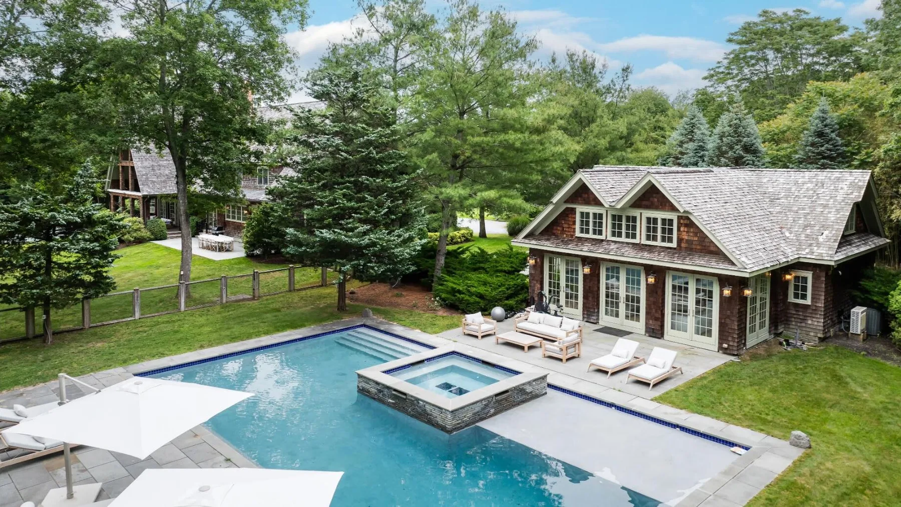 Una piscina en el patio con un spa cuadrado elevado junto a una casa.