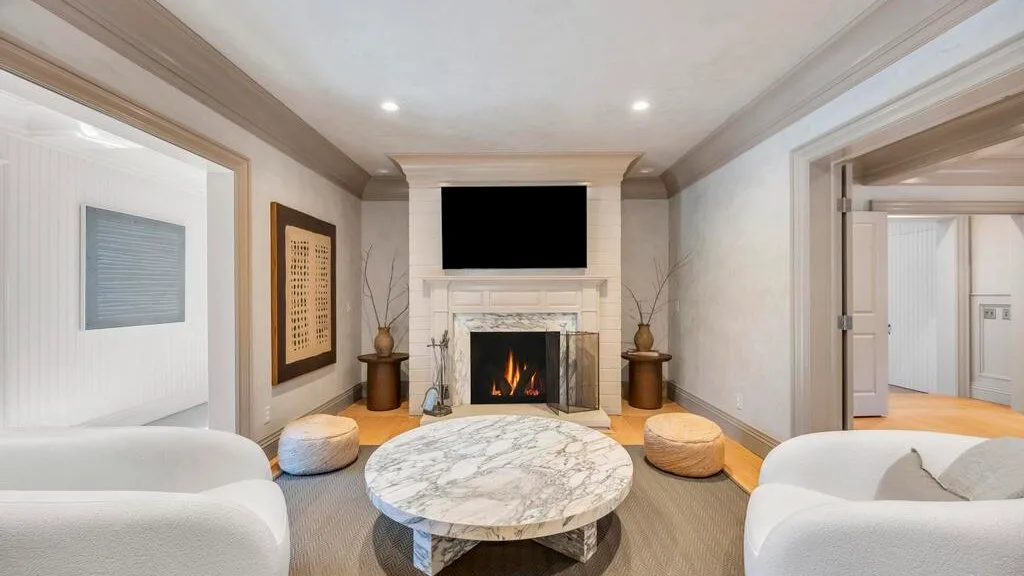 Una sala de estar con un televisor sobre una chimenea y una mesa de centro redonda.