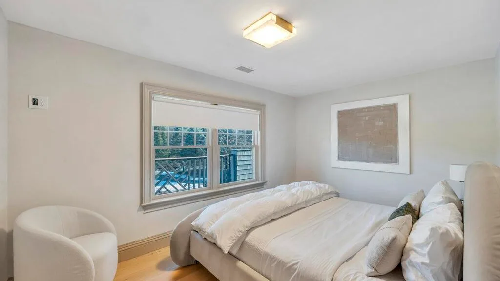 Un dormitorio con una cama ordenada y una ventana grande.