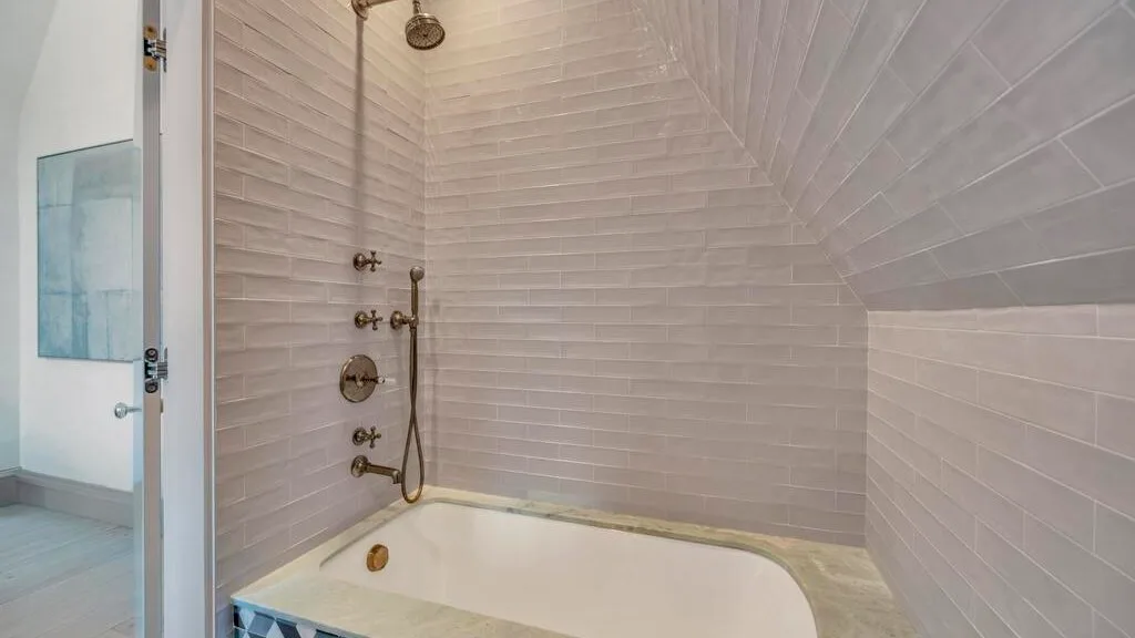 Un baño con bañera y accesorios de ducha montados en la pared.