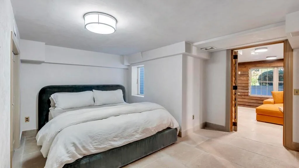 Un dormitorio con una cama junto a una puerta abierta a una zona de estar.