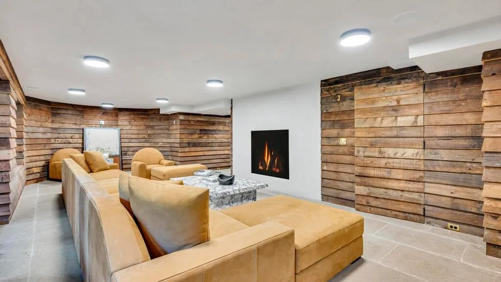 Una sala de estar con asientos color canela alrededor de una mesa baja y una chimenea empotrada.