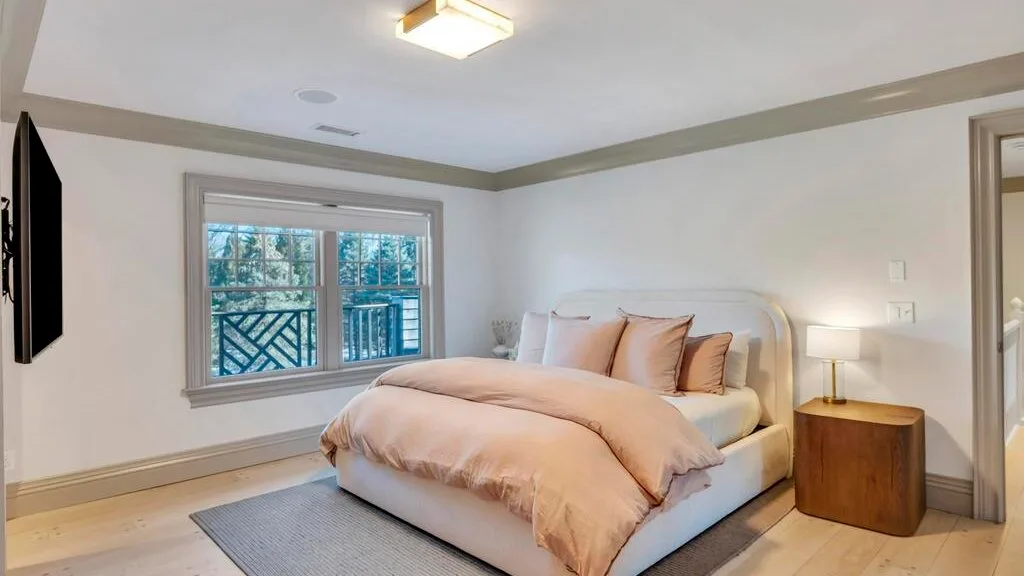 Un dormitorio con una cama, una ventana y una pequeña mesa de noche.
