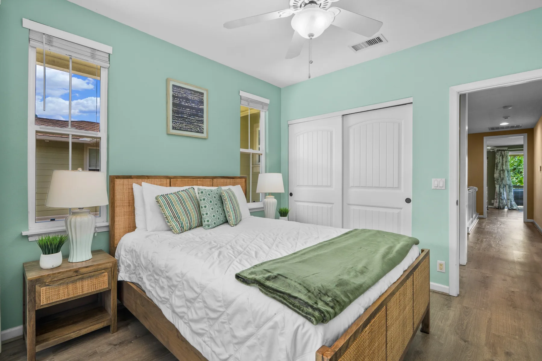 Un dormitorio con una cama, puertas blancas de armario y paredes verde menta.