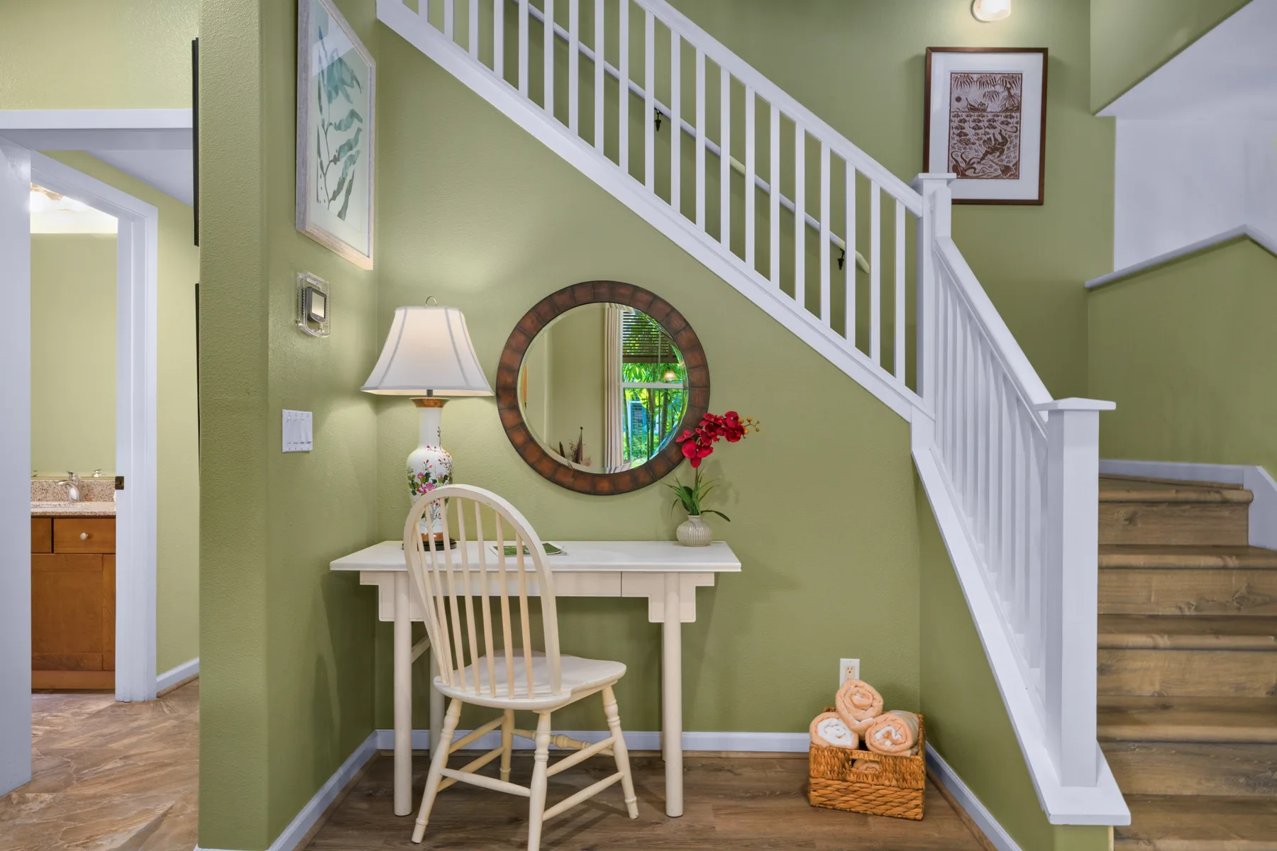 Un recibidor interior con una escalera, una mesa pequeña y un espejo de pared.