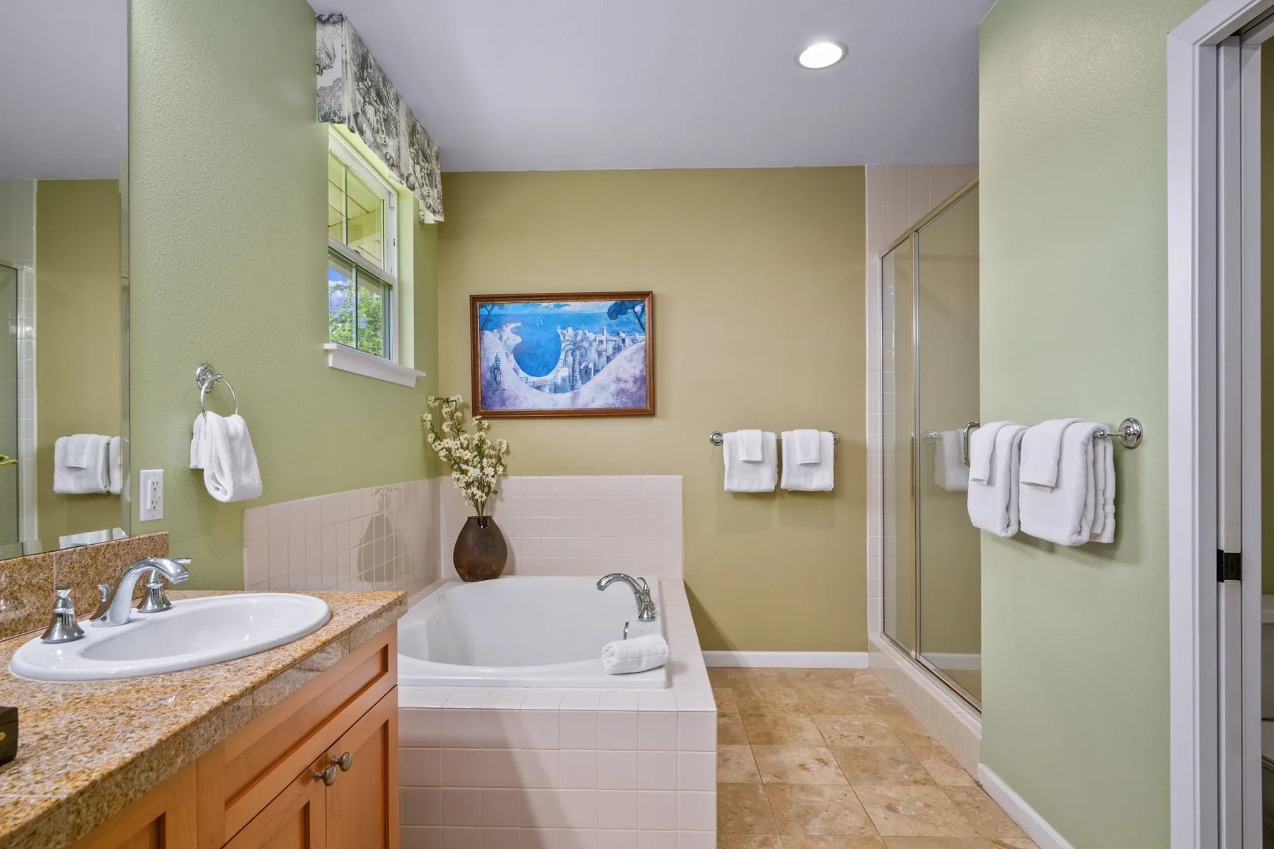Un baño con bañera, lavabo y ducha con paneles de vidrio.