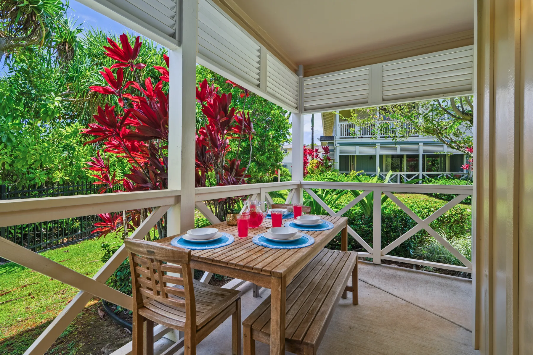 Una zona de comedor exterior cubierta con una mesa de madera y vistas al jardín.