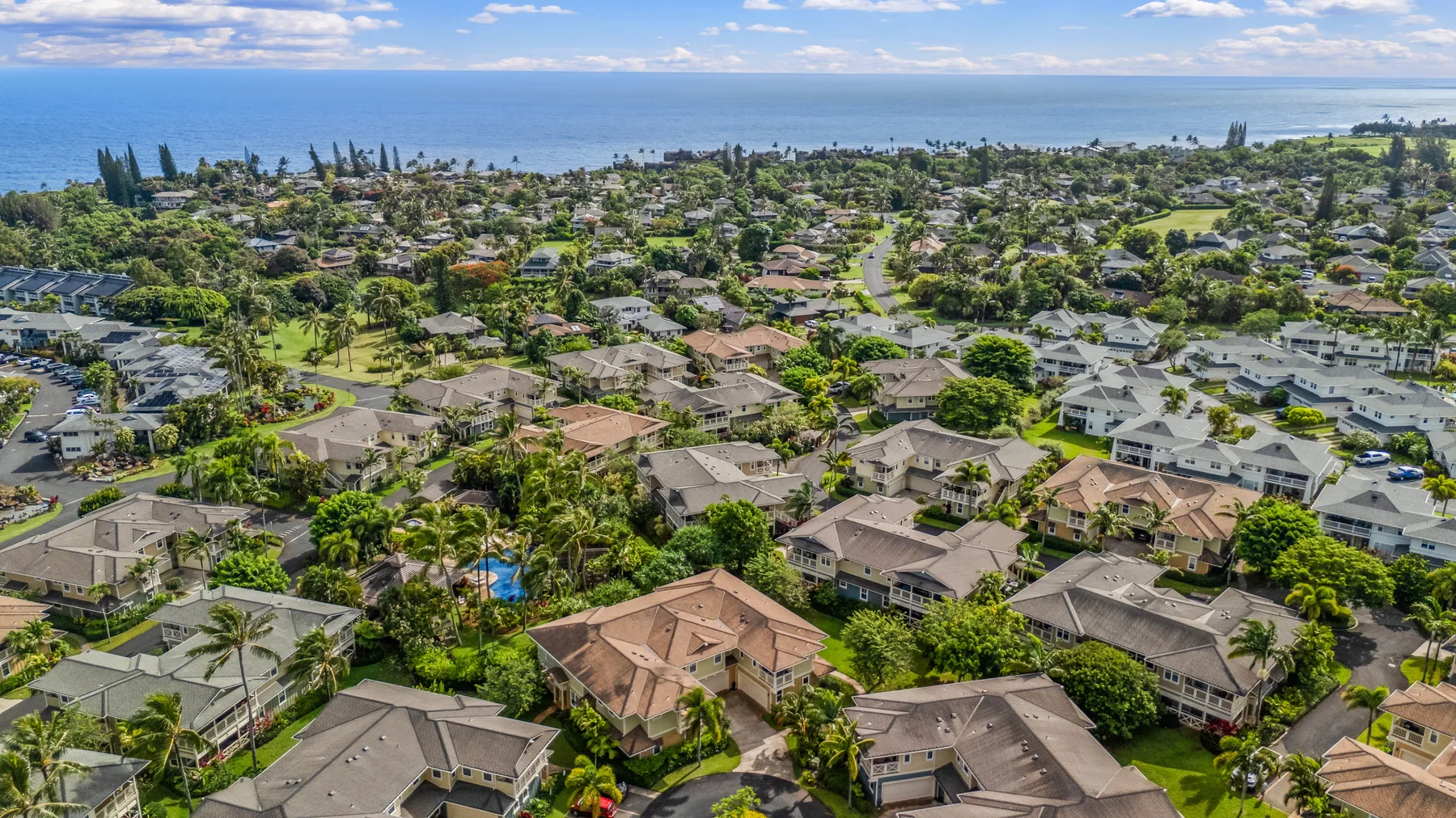 Vista aérea de un barrio residencial costero con el océano a lo lejos.