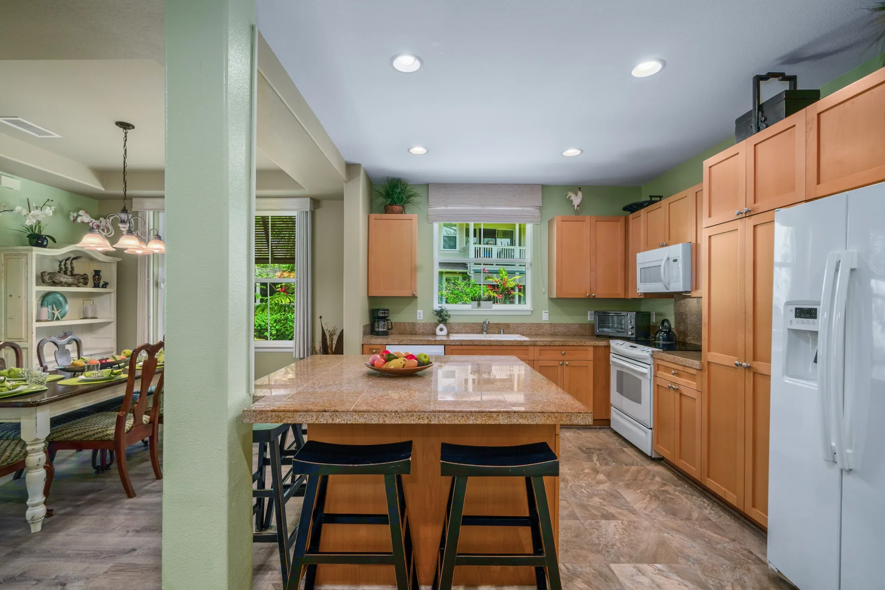 Una cocina luminosa con una isla central, gabinetes de madera y electrodomésticos de acero inoxidable.