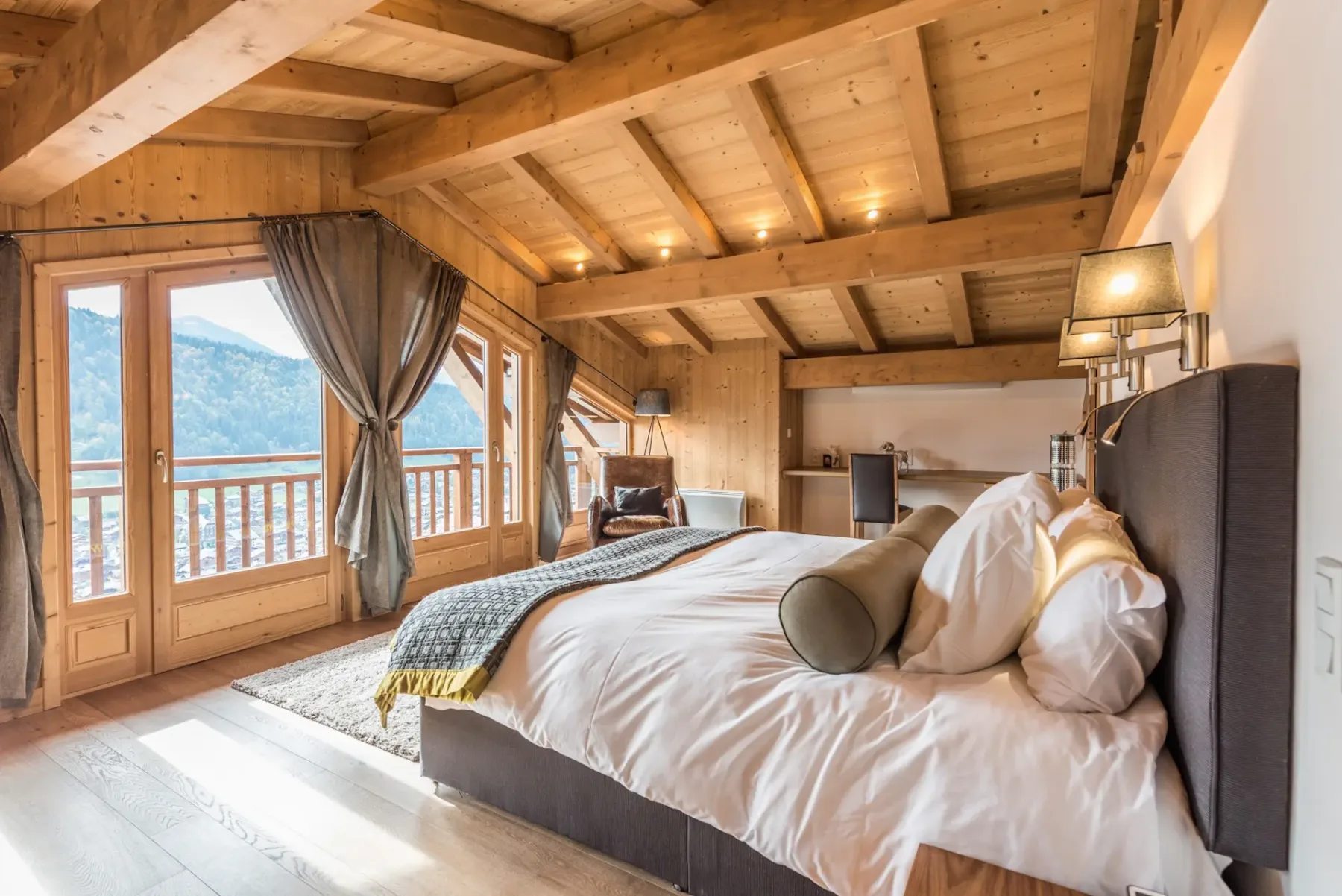 Un dormitorio con una cama grande, techo de madera y ventanas que dan a un balcón.