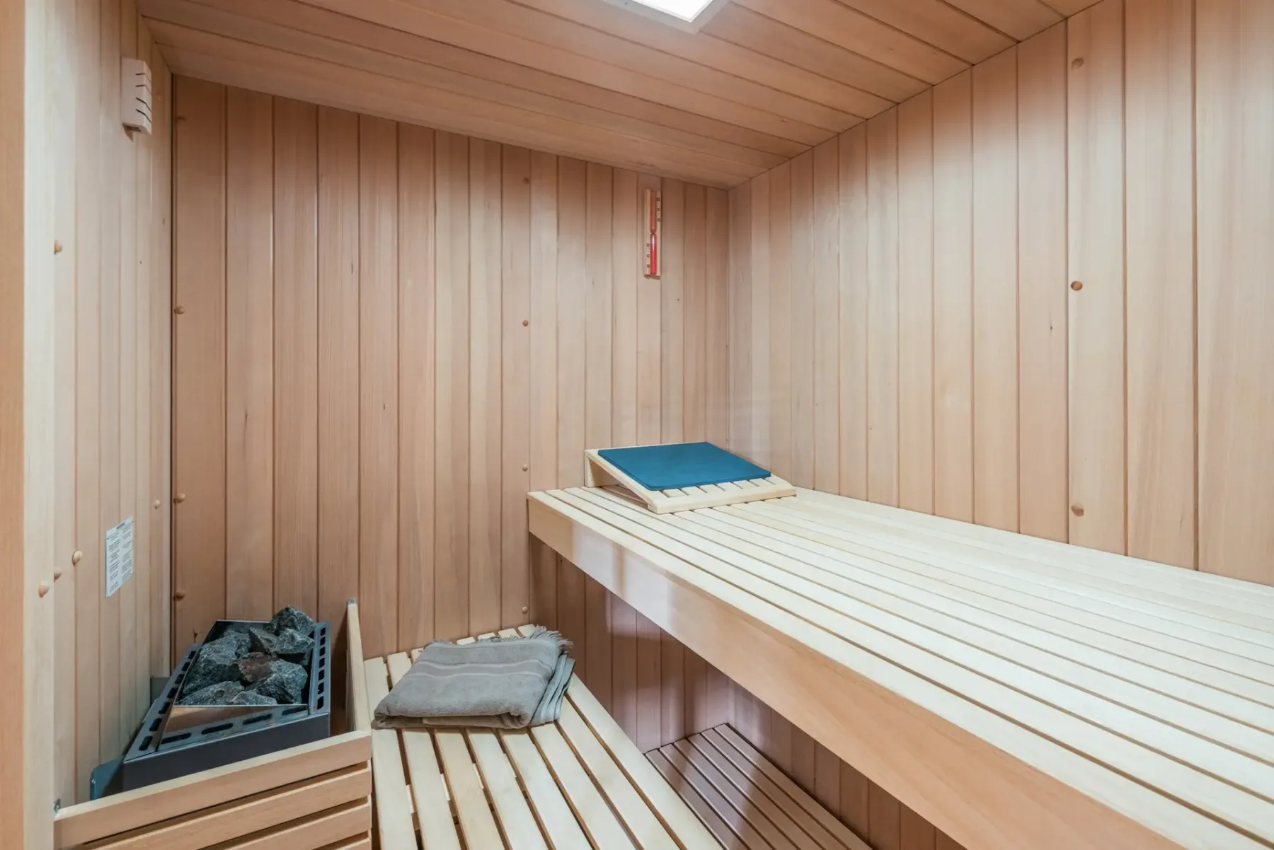 Una sauna revestida de madera con un calentador y bancos a distintos niveles.