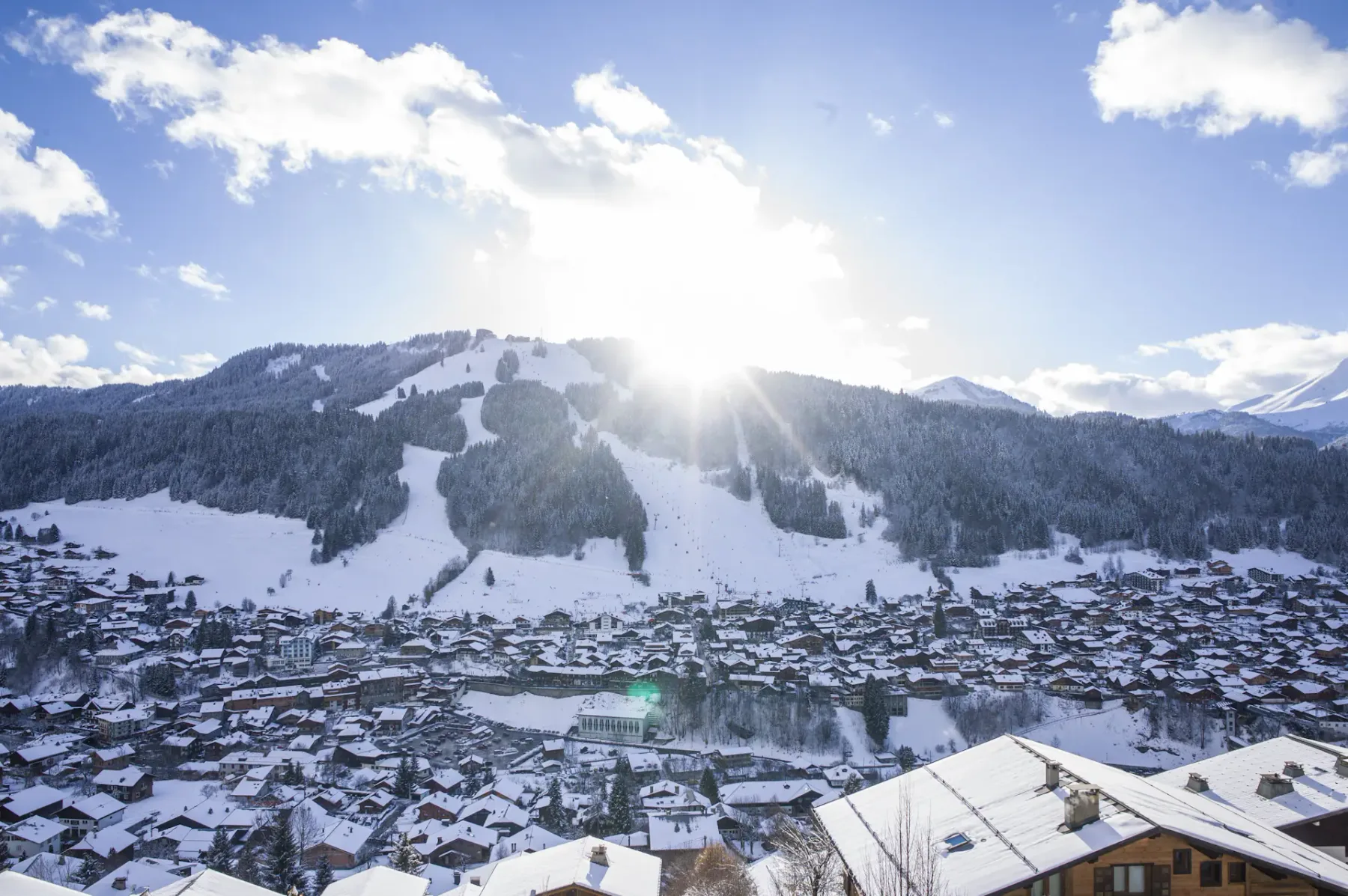 Un pueblo nevado se encuentra bajo pistas de esquí y un cielo invernal luminoso.