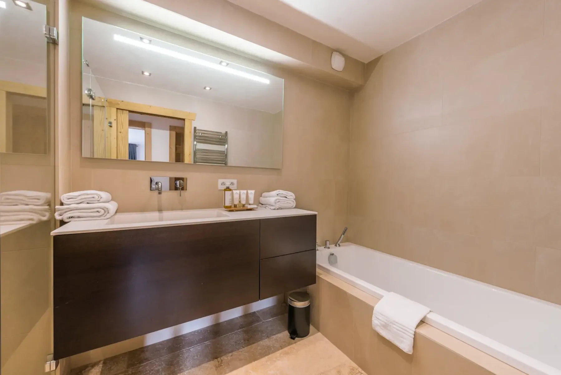 Un baño con bañera, lavabo, espejo y toallas dobladas cuidadosamente.