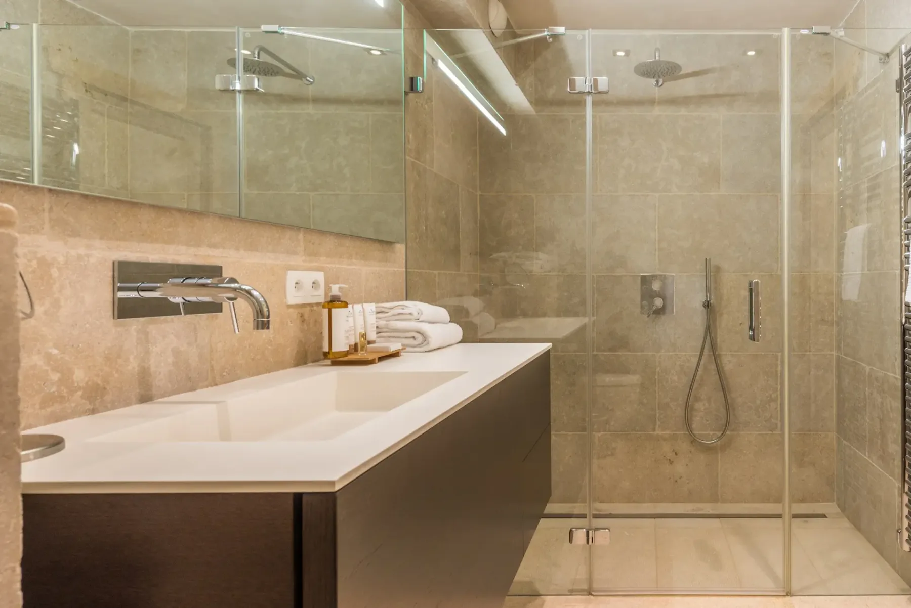 Un baño moderno con un amplio lavabo y una ducha con mampara de cristal.