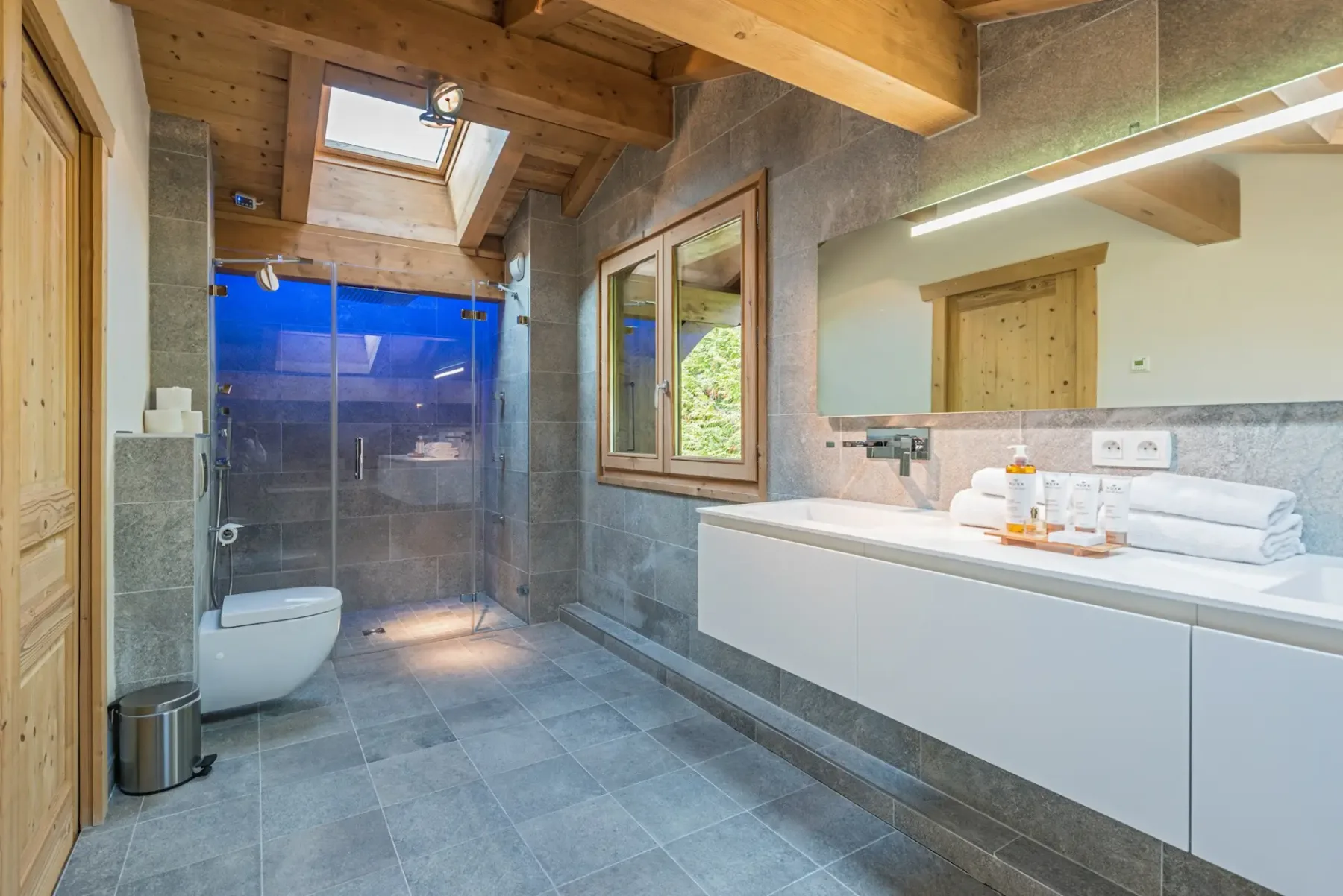 Un baño moderno tiene ducha, inodoro y toallas junto al lavabo.