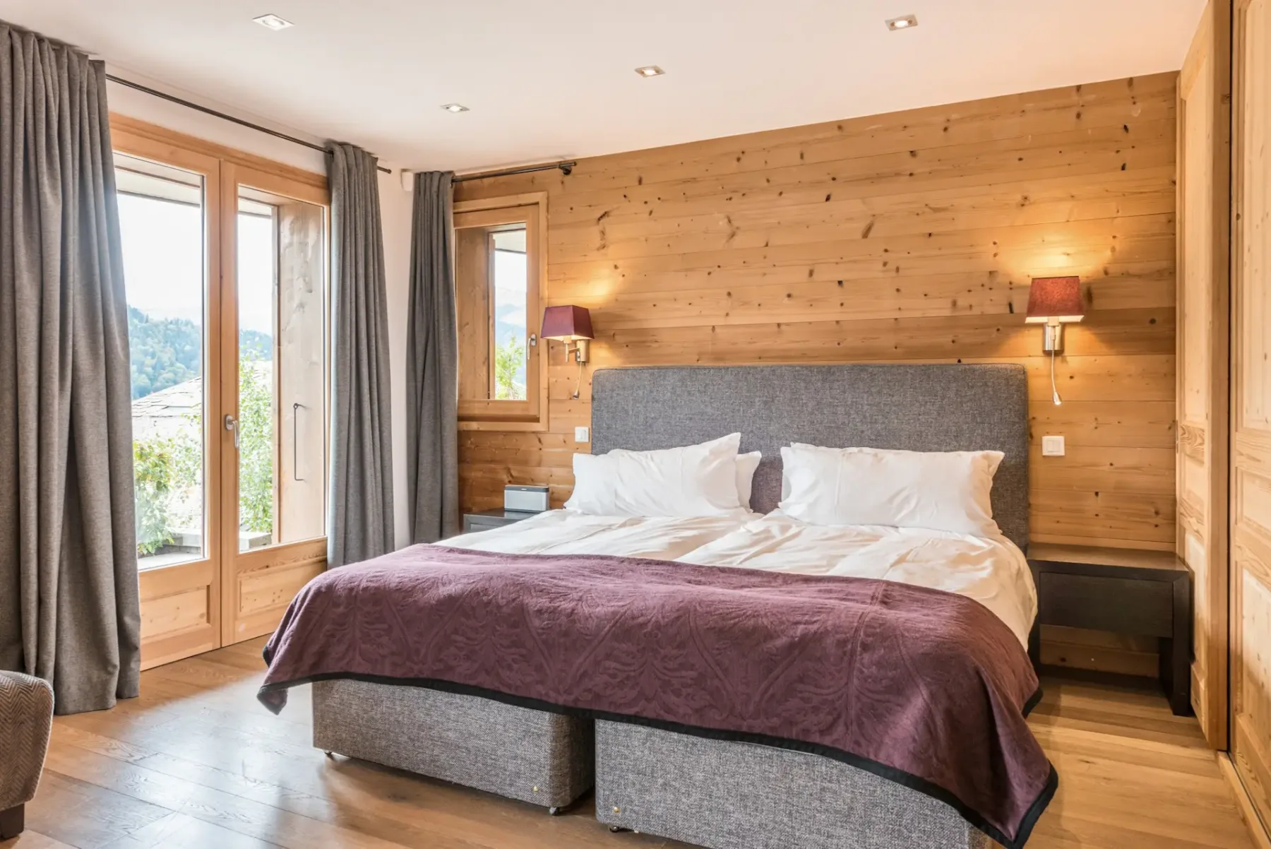 Un dormitorio con una cama grande, paredes revestidas de madera y ventanas.