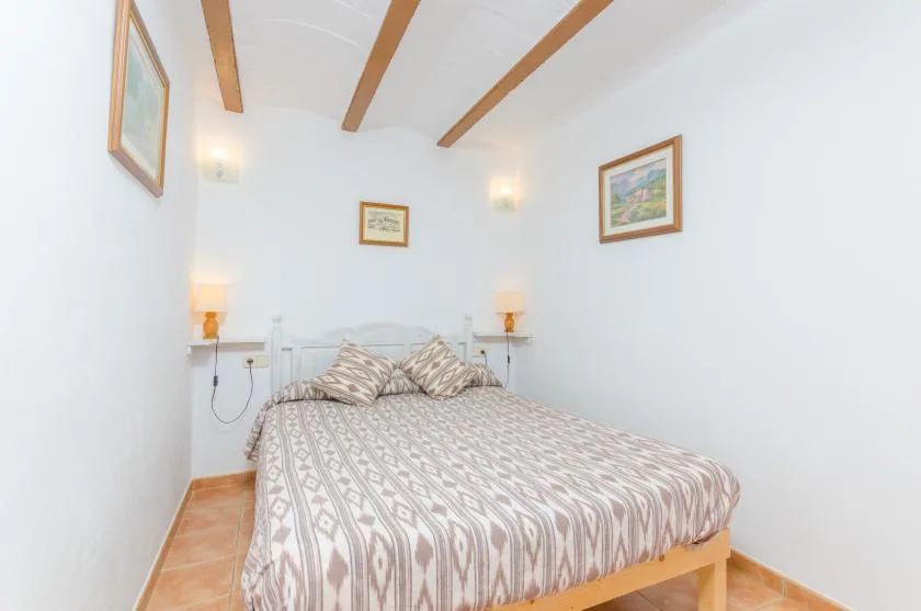 Un dormitorio con una cama estampada, lámparas de noche y cuadros.