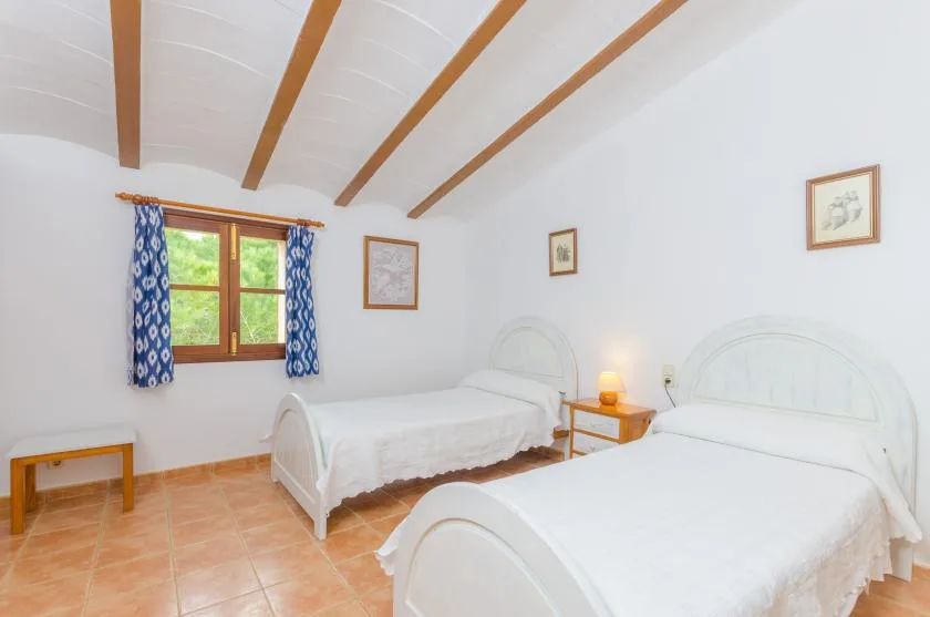 Un dormitorio luminoso con dos camas y una ventana con cortinas azules.