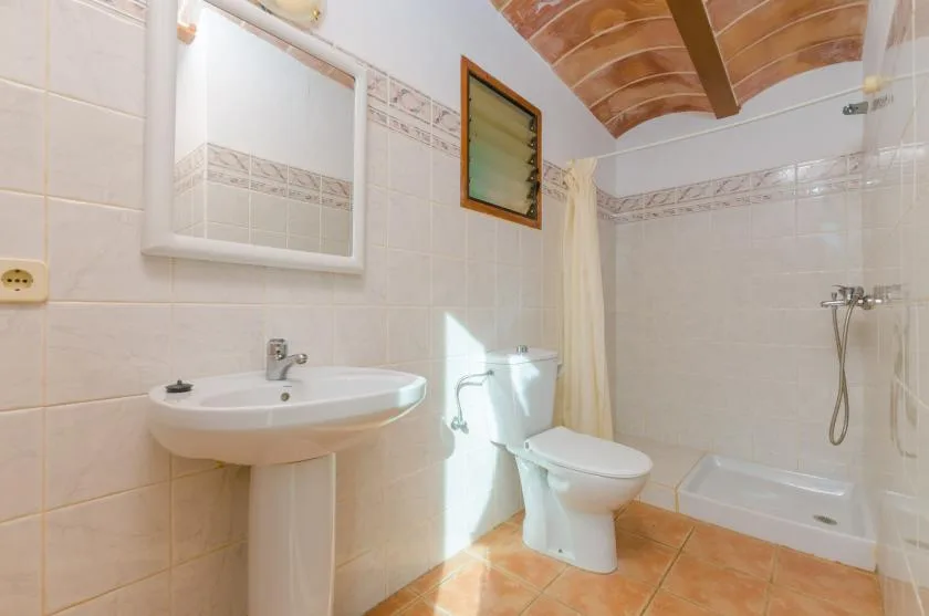 Un baño alicatado con lavabo de pedestal, inodoro y bañera.