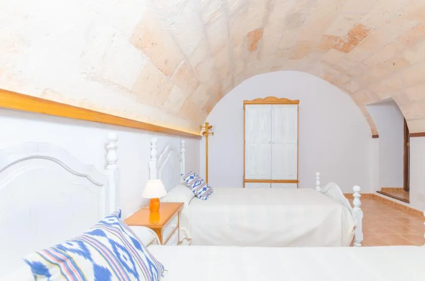 Un dormitorio luminoso con una cama blanca bajo un techo curvo.