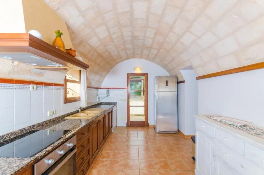 Una cocina con gabinetes de madera, encimeras de azulejo y un refrigerador.