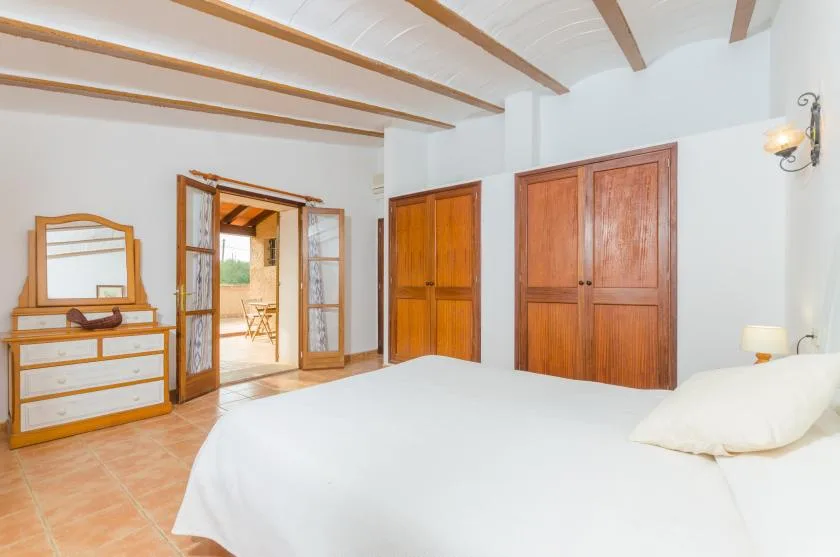 Un dormitorio con una cama, armarios de madera y una puerta abierta.