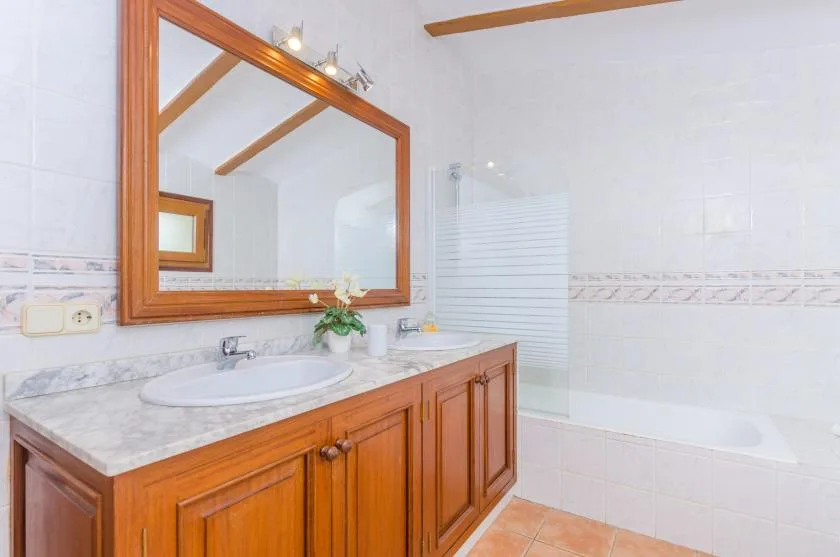 Un baño con un tocador de madera, un espejo grande y una bañera.