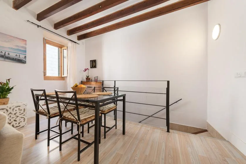 A dining area with a table and chairs beside a black metal railing.
