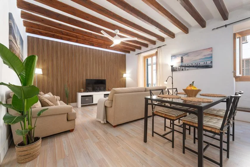 A living and dining area with seating, a table, and exposed ceiling beams.