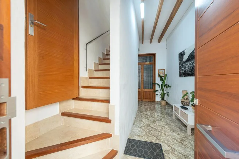 An interior hallway with a staircase, wooden doors, and a small seating area.
