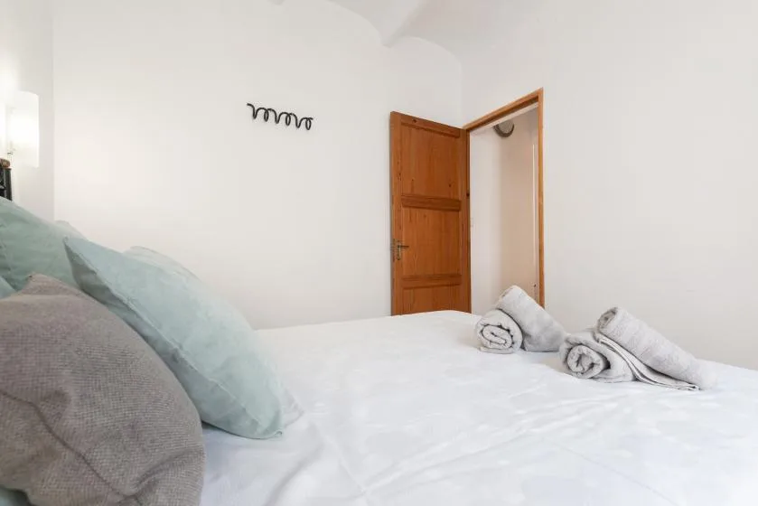 A bedroom with a neatly made bed and an open wooden door.
