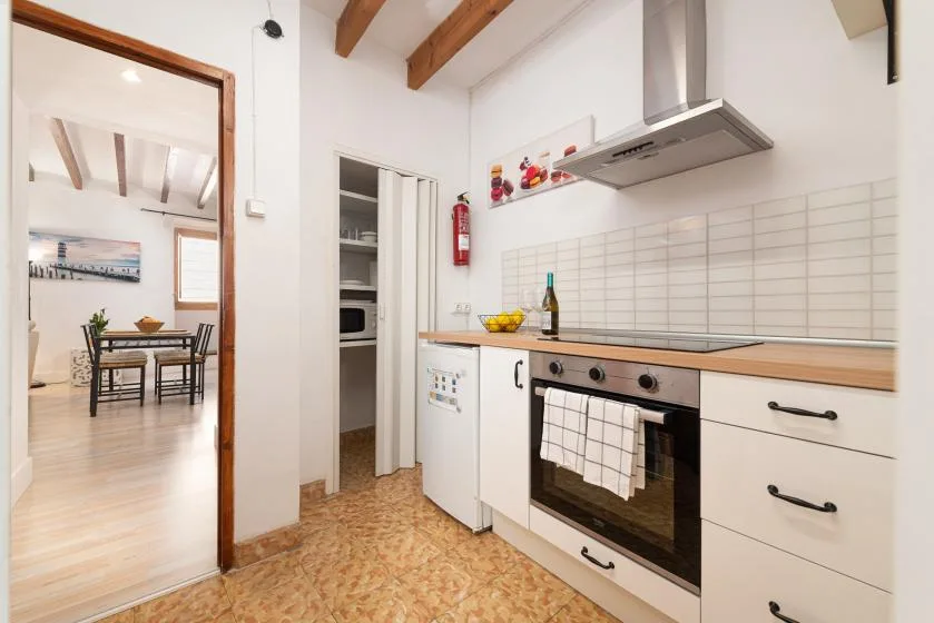 A bright kitchen with an oven, tiled backsplash, and wooden ceiling beams.