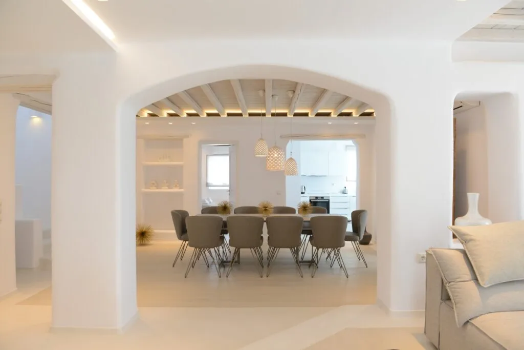 Un comedor luminoso con una mesa larga y asientos bajo un arco.