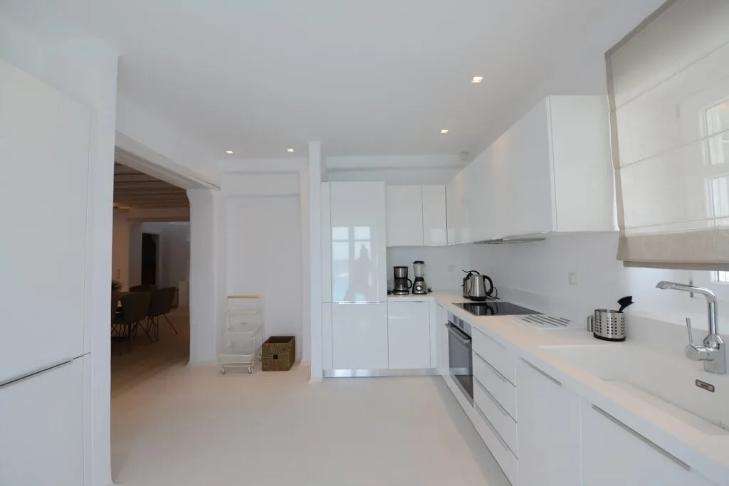 Una cocina moderna y luminosa con gabinetes blancos y pequeños electrodomésticos.