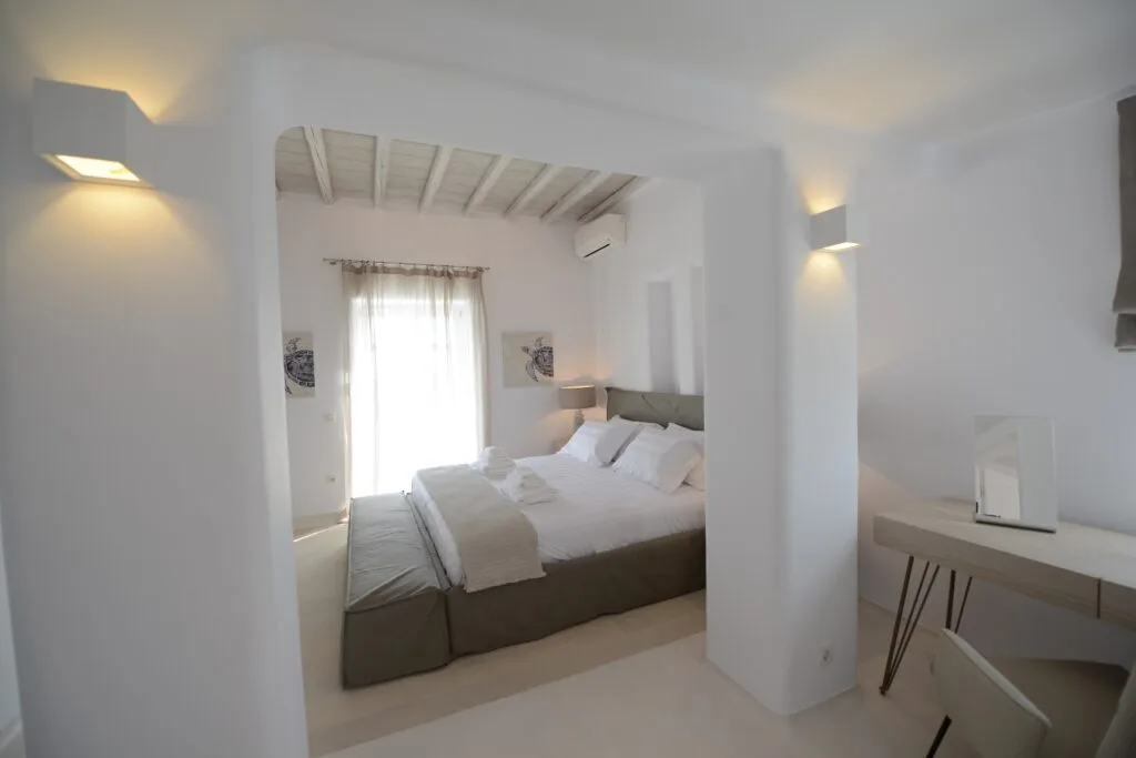 Un dormitorio luminoso con una cama doble junto a una ventana alta.