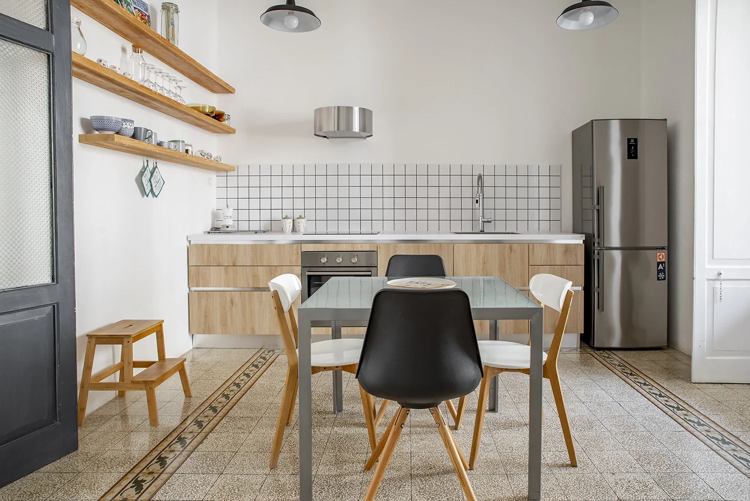 Una cocina y zona de comedor con mesa, sillas y estantes abiertos.