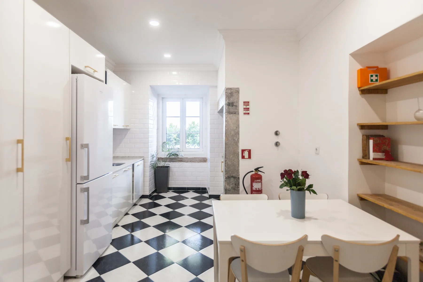 A bright kitchen and dining area with a black-and-white tiled floor.