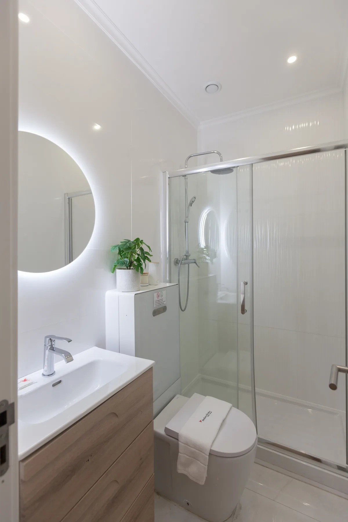 Un baño luminoso con lavabo, inodoro y ducha de vidrio.