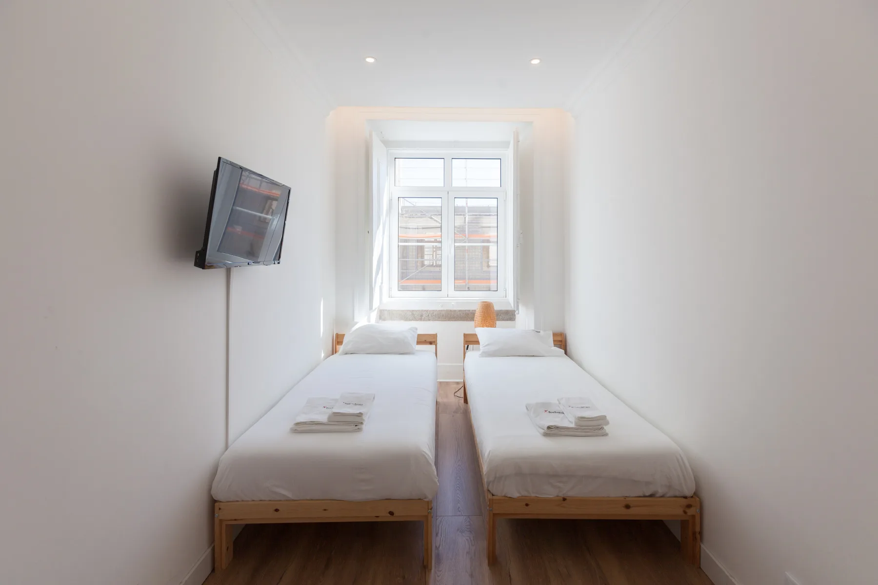 A bright bedroom with two single beds and a window.