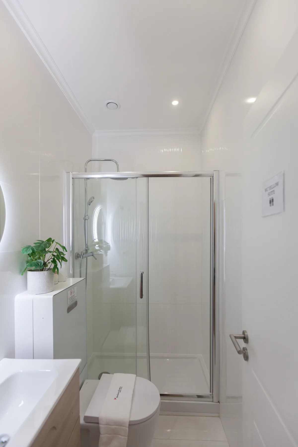 Un baño luminoso con una ducha de cristal y un lavabo.