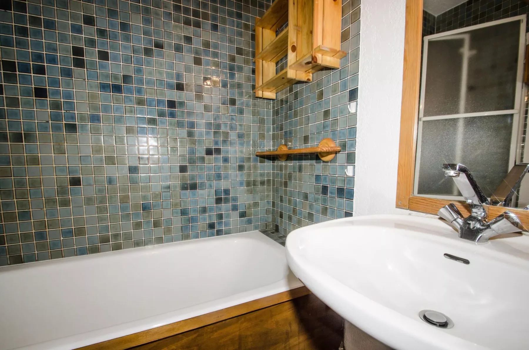 A bathroom with a bathtub, tiled wall, and sink.