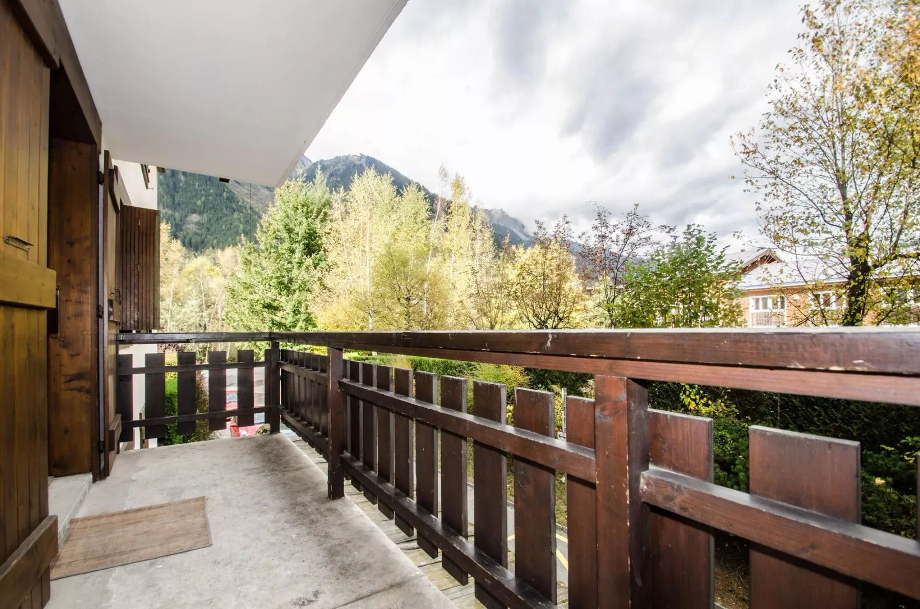 A covered balcony overlooks trees and a wooded mountain.