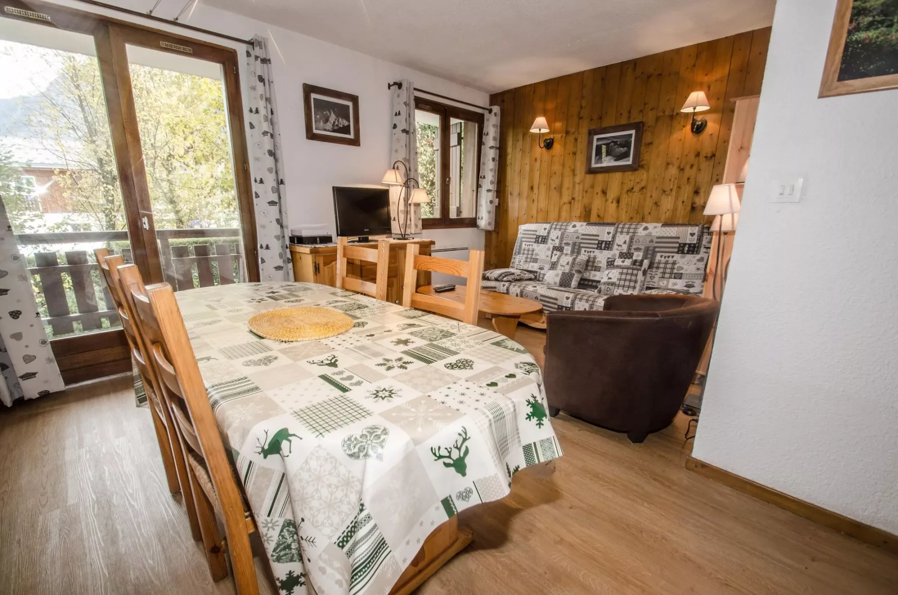 A dining and sitting area with a table beside a wood-paneled wall.