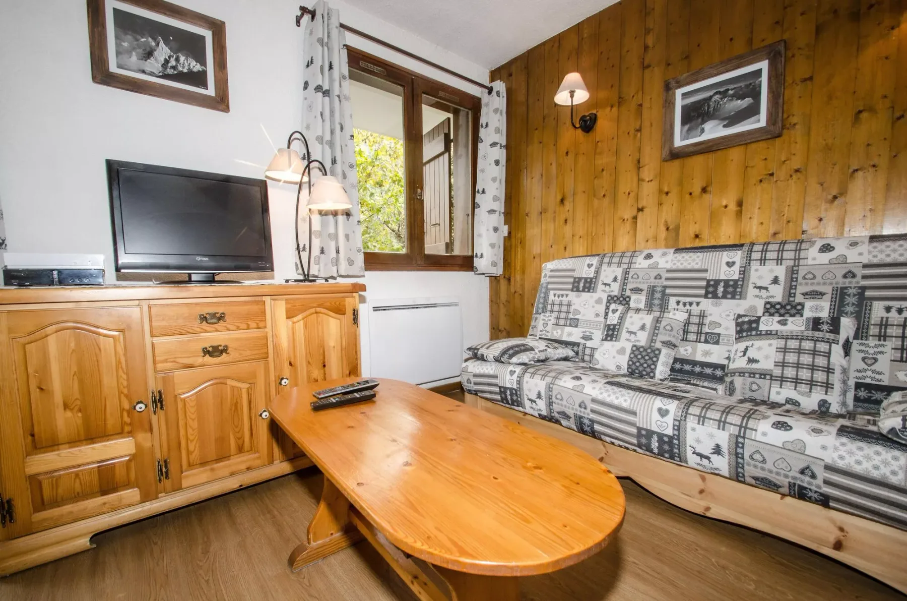 A living room with patterned seating, a wooden coffee table, and a television.