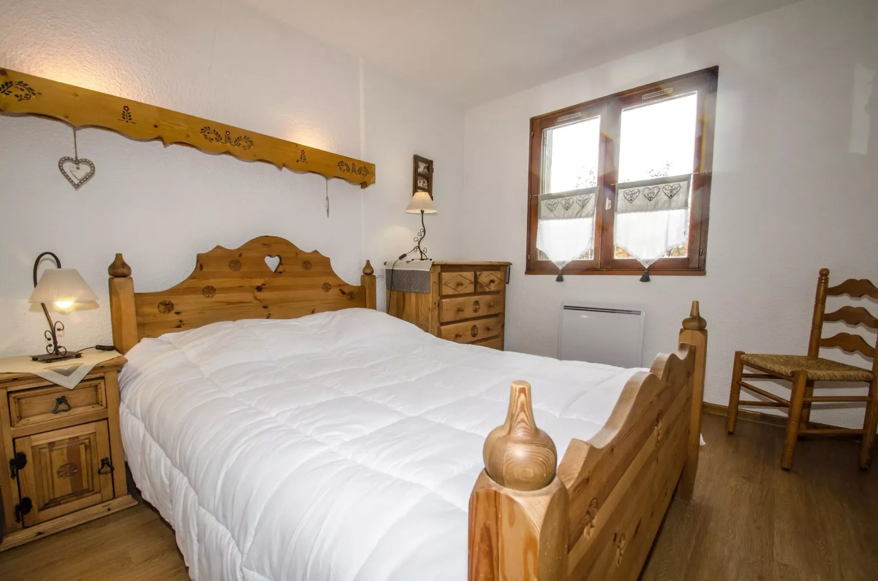 A bedroom with a wooden bed, bedside tables, and a window.