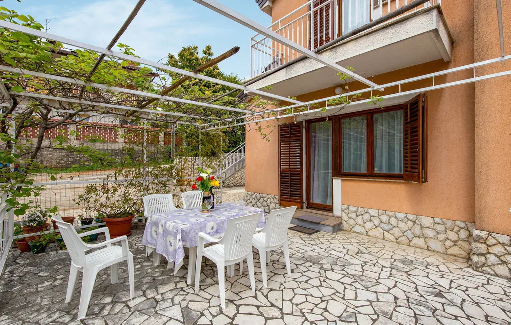 A paved outdoor patio with a table and seating beside a house.