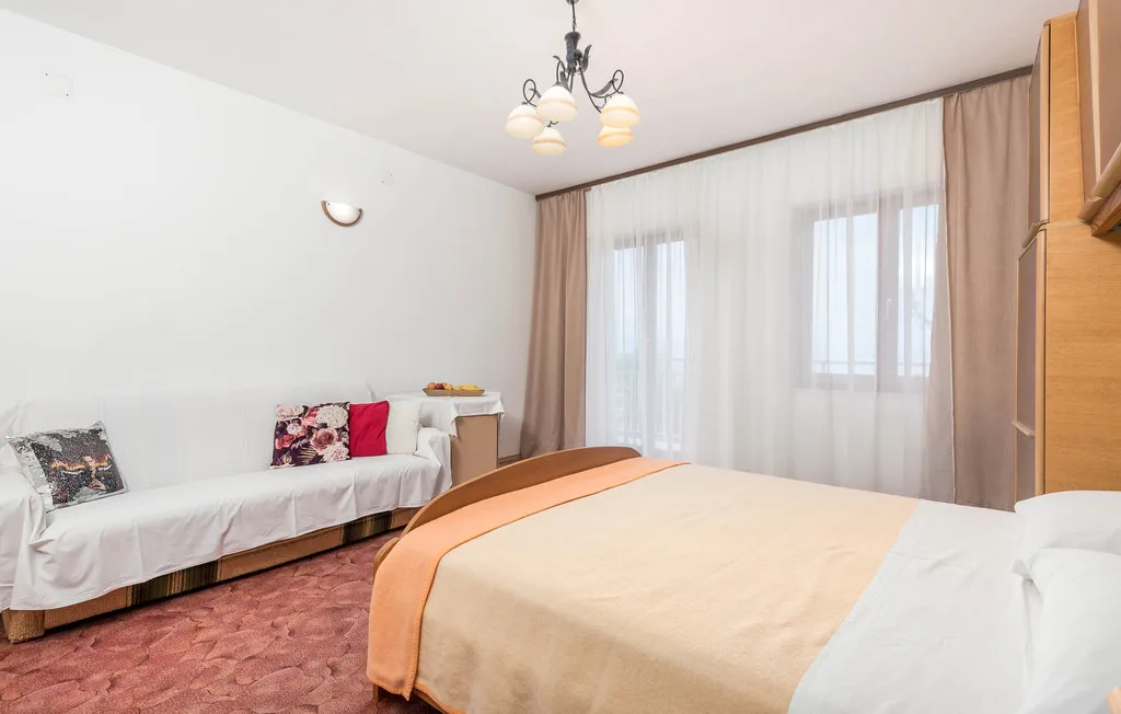 A bedroom with a large bed, a sofa, and curtained windows.