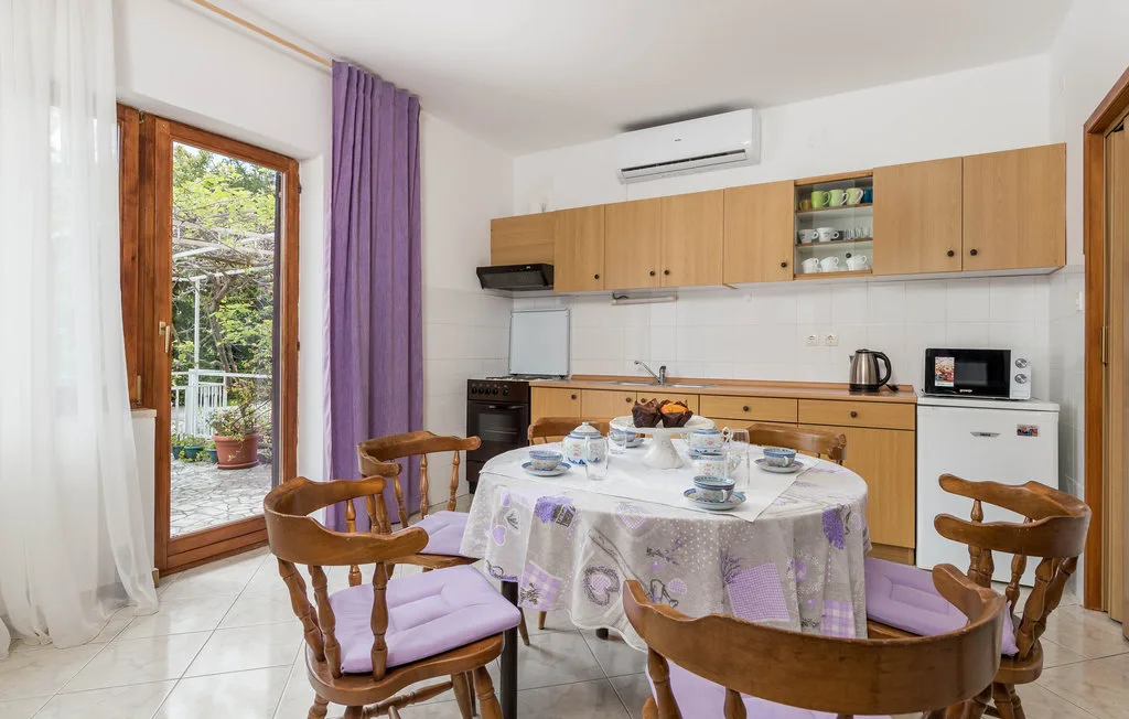 A dining area with a round table set in front of wooden kitchen cabinets.