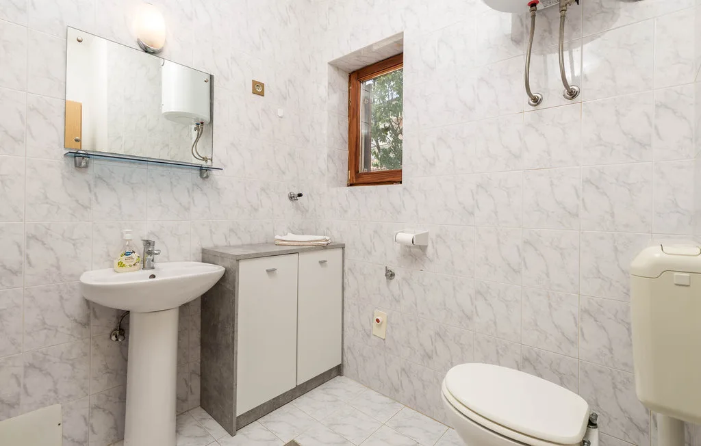 A tiled bathroom with a sink, cabinet, and toilet.