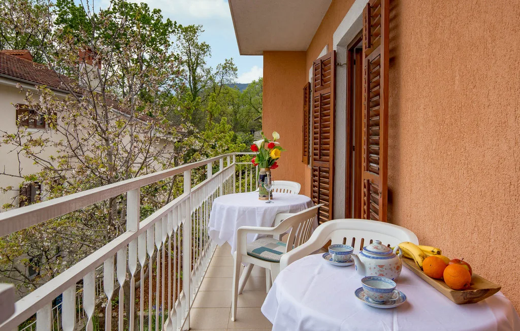 A balcony dining area with white tablecloths and leafy views.